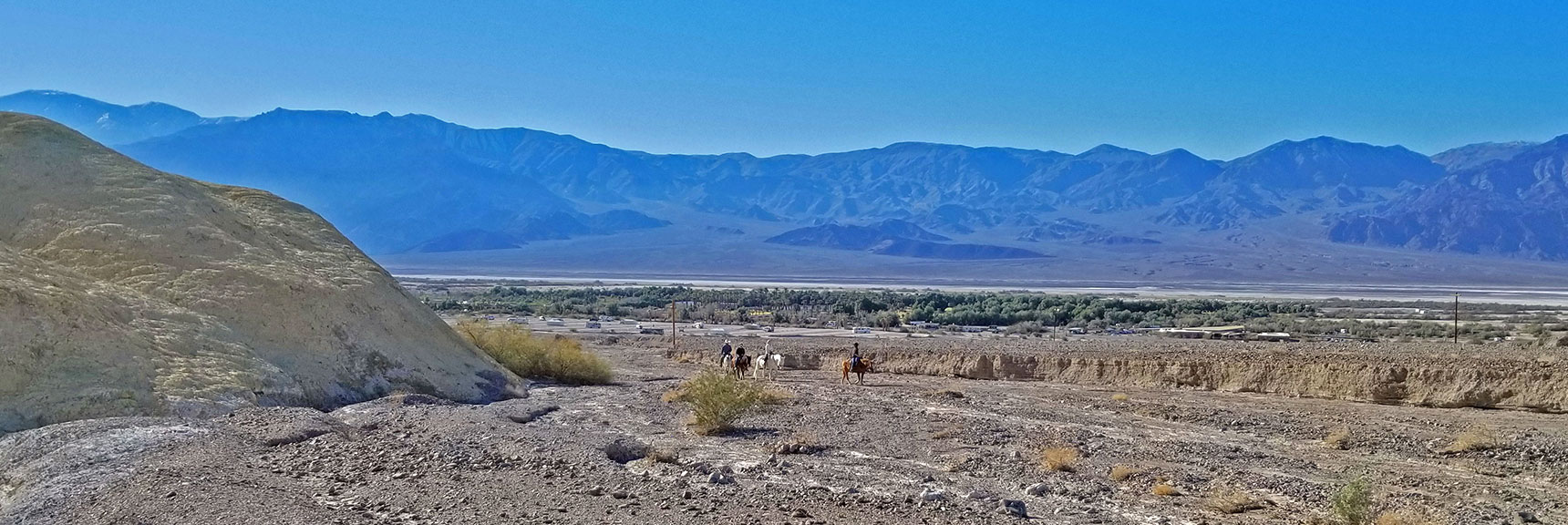 Group Approaching on Horseback. Furnace Creek Ranch with Panamint Range Background. | Tea House & Table Rock Circuit | Furnace Creek | Death Valley National Park, California